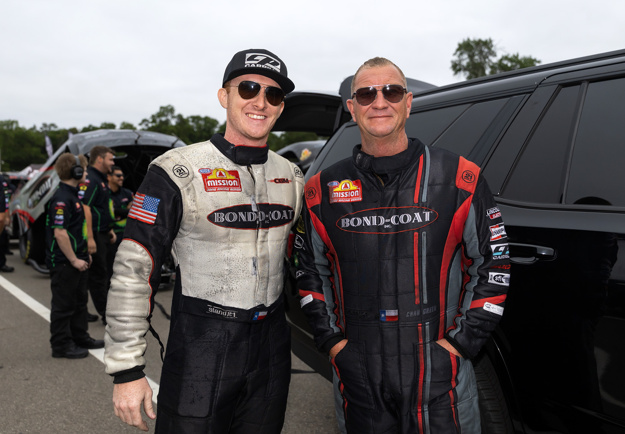 Chad and Hunter Green in firesuits, side by side in the pits