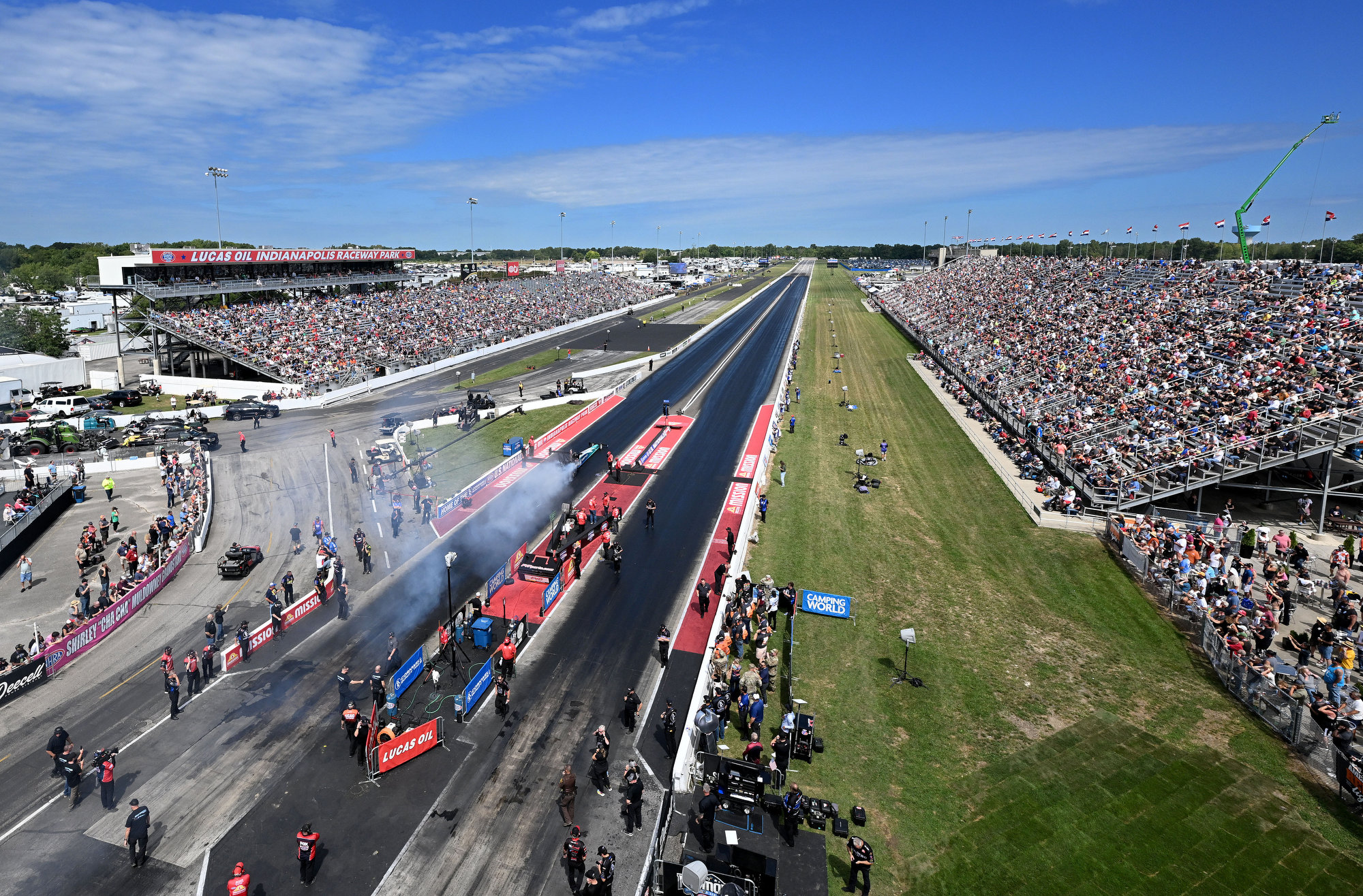 Full grandstands on both sides of the track as two cars launch