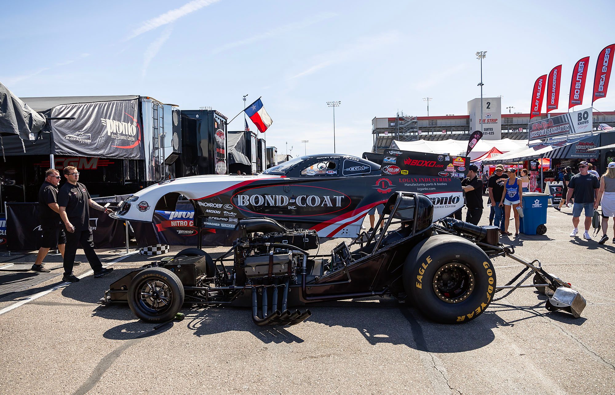 The black Bond-Coat Funny Car sits in the pit area under the awning