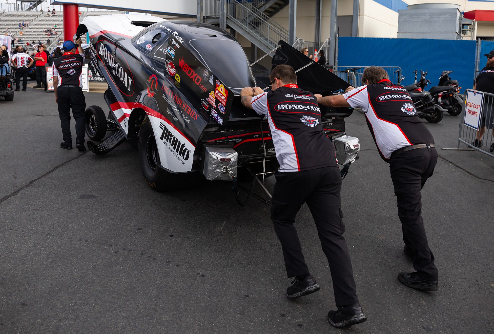 The crew pushes the Bond-Coat Funny Car back through the pits