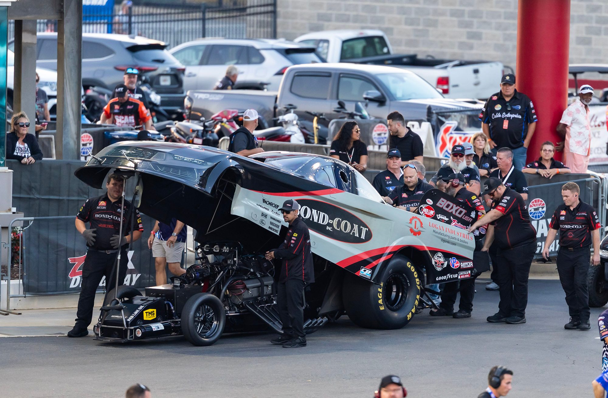 Body up in the staging lanes, fans along the fence behind the crew