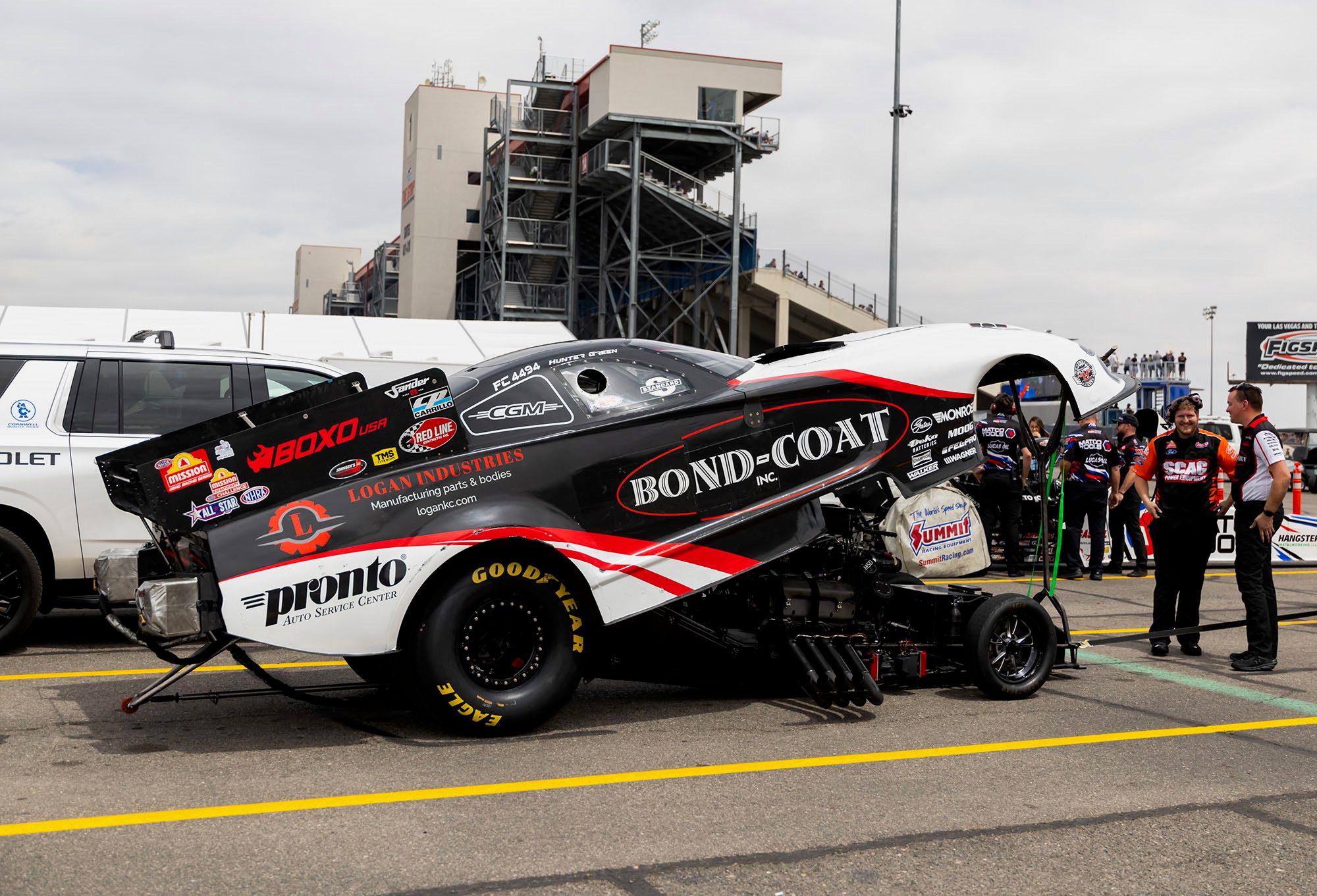 The Bond-Coat Funny Car waits in the staging lanes with the crew behind it