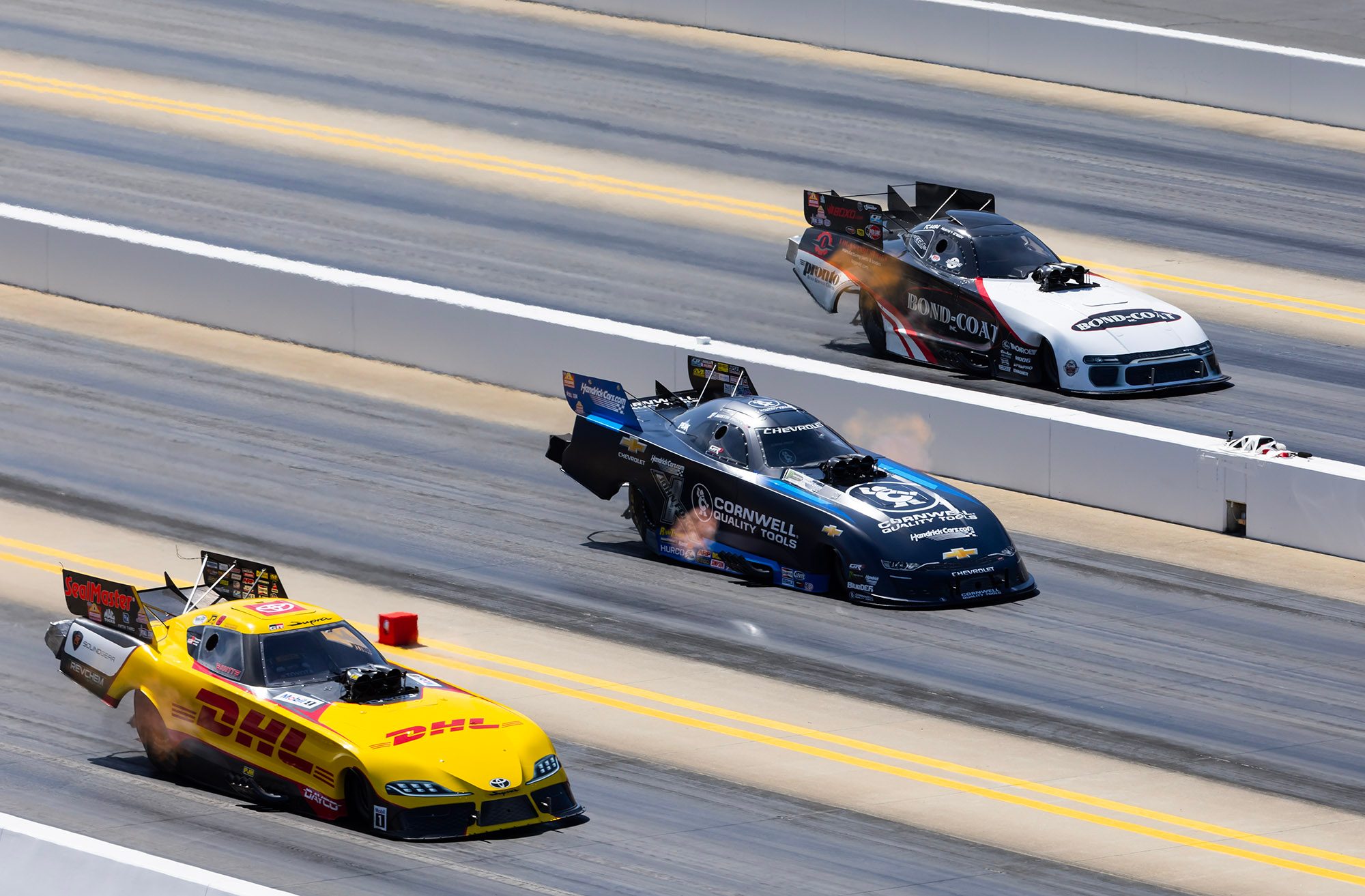 Three Funny Cars at speed, the Bond-Coat car in the far lane