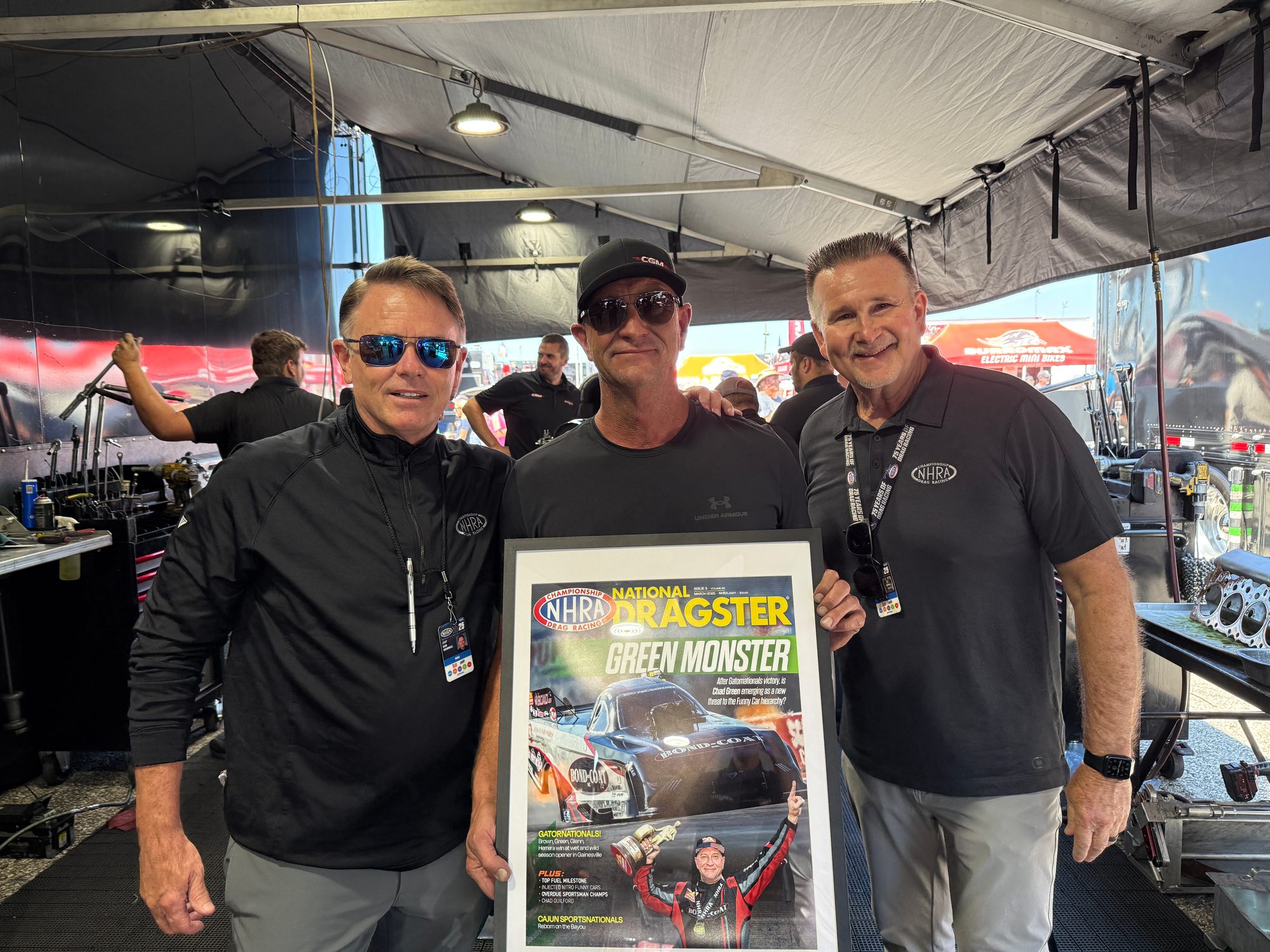 A framed National Dragster cover is presented under the pit awning